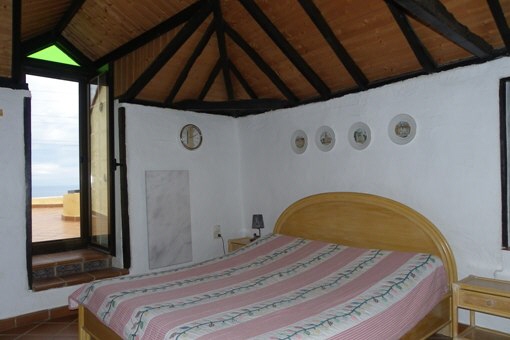 Dormitorio con techo alto con vigas y calefacción de mármol